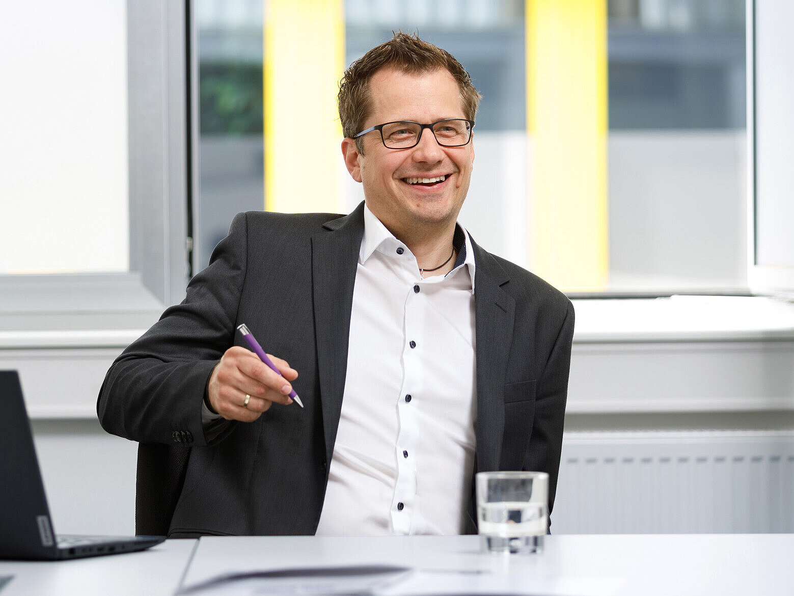 Smiling employee in a meeting room with a laptop.
